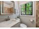 Bathroom featuring granite counters, modern sink, decorative mirror, and a window with an exterior view at 201 W Alva St, Tampa, FL 33603