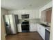 Updated kitchen featuring white cabinets, stainless steel appliances, and wood flooring at 209 Corkwood Ln, Oldsmar, FL 34677