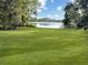 Expansive backyard with lush lawn and mature trees bordering a serene lake at 2103 N Golfview Dr, Plant City, FL 33566