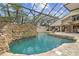 Enclosed pool area boasts a rock waterfall, covered patio, and lounging area perfect for relaxation at 2103 N Golfview Dr, Plant City, FL 33566