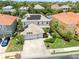 Aerial view showcases a home with a three-car garage, solar panels, and manicured landscaping in a desirable neighborhood at 2228 Hannah S Way, Dunedin, FL 34698