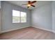Well-lit bedroom with light hardwood floors, ceiling fan, and a large window providing ample natural light at 2228 Hannah S Way, Dunedin, FL 34698