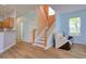 Inviting living room with wood floors, staircase, natural light, and comfortable seating by the window at 2228 Hannah S Way, Dunedin, FL 34698