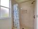 Shower with marble tile, shower niche, and a window providing natural light at 2228 Hannah S Way, Dunedin, FL 34698