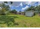Expansive backyard with lush lawn, mature trees, shed, and partially fenced perimeter at 2415 York N St, St Petersburg, FL 33710