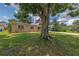 View of the home from under a large tree with American flag in the front yard at 2415 York N St, St Petersburg, FL 33710