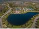 Aerial view of community clubhouse, pool, parking, lake, and lush surroundings at 29038 Picana Ln, Wesley Chapel, FL 33543