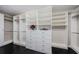 Spacious walk-in closet with custom shelving, drawers, hanging rods, and dark wood-look floors at 29038 Picana Ln, Wesley Chapel, FL 33543