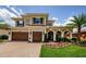 Beautiful two-story home featuring a three-car garage, arched entryway, and manicured landscaping at 29038 Picana Ln, Wesley Chapel, FL 33543