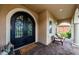 Inviting front porch featuring decorative iron doors, stone flooring, and seating area at 29038 Picana Ln, Wesley Chapel, FL 33543