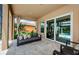 Covered patio has tiled flooring and stylish furniture overlooking a landscaped yard and the pool area at 29038 Picana Ln, Wesley Chapel, FL 33543
