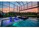 Inviting screened pool features a spa, submerged seating, and scenic views of the lake and sky at 29038 Picana Ln, Wesley Chapel, FL 33543