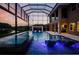 Gorgeous screened pool at dusk features a waterfall, spa, and ambient lighting for a luxurious experience at 29038 Picana Ln, Wesley Chapel, FL 33543