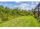 A black fence borders the property, with lush green grass providing a tranquil backyard atmosphere at 30326 Ceasar Park Dr, Wesley Chapel, FL 33543
