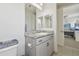 Bathroom vanity with granite countertop, grey cabinetry, undermount sink, two mirrors and nearby bedroom at 30326 Ceasar Park Dr, Wesley Chapel, FL 33543