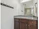 Bathroom vanity with dark wood cabinets, granite counters, large mirror and towel hooks at 30326 Ceasar Park Dr, Wesley Chapel, FL 33543