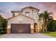 Two-story home featuring a two-car garage, neutral stucco, and a tile roof at 30326 Ceasar Park Dr, Wesley Chapel, FL 33543