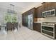 Bright eat-in kitchen featuring stainless steel appliances, dark wood cabinets, and a modern chandelier at 30326 Ceasar Park Dr, Wesley Chapel, FL 33543
