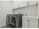 Modern laundry room featuring a gray washer/dryer set, white cabinetry, and a sink with stylish fixtures at 30326 Ceasar Park Dr, Wesley Chapel, FL 33543