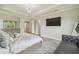Bright main bedroom with tray ceilings, wood floors, television, and ensuite bathroom at 30326 Ceasar Park Dr, Wesley Chapel, FL 33543