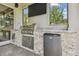 Outdoor kitchen on the patio with a built-in grill, mini fridge, and a TV at 30326 Ceasar Park Dr, Wesley Chapel, FL 33543
