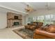 Spacious living room featuring a vaulted ceiling, exposed beams, a brick fireplace and a cozy leather sofa at 3262 Westcott Ct, Palm Harbor, FL 34684