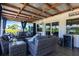 Relax in the spacious covered porch with wicker seating, blue curtains, and backyard views at 3312 Kenmore Dr, Sarasota, FL 34231