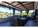 Cozy covered porch with wicker furniture, curtains, and a view of the lake and landscaping creates an inviting outdoor space at 3312 Kenmore Dr, Sarasota, FL 34231
