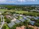 This aerial view features tennis courts, a swimming pool, and a golf course surrounded by lush greenery at 335 Palmdale Dr, Oldsmar, FL 34677