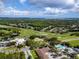 An aerial view shows a well-manicured golf course with lush greens, a clubhouse, and a swimming pool on a sunny day at 335 Palmdale Dr, Oldsmar, FL 34677