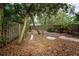 Lush backyard with mature trees, a rustic fence, and a 'For Sale' sign at 335 Palmdale Dr, Oldsmar, FL 34677