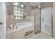 Bathroom featuring a white tub under a window and glass shower with gold trim at 335 Palmdale Dr, Oldsmar, FL 34677