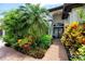 Landscaped front entrance with mature trees, flowering shrubs, and brick walkway to double glass doors at 335 Palmdale Dr, Oldsmar, FL 34677