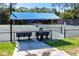 View of community tennis court featuring shaded bench seating and manicured landscaping at 335 Palmdale Dr, Oldsmar, FL 34677