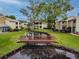 Beautiful waterfront view of pond and condos with mature landscaping and a wooden bridge at 4114 Pinelake Ln # 202, Tampa, FL 33618