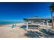Scenic beach view with picnic tables, lounge chairs, and palm trees, perfect for enjoying the beautiful ocean scenery at 5030 Herring Ct, New Port Richey, FL 34652