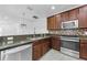 Kitchen area showcasing stainless steel appliances, dark wood cabinets, granite countertops, and a decorative light fixture at 5030 Herring Ct, New Port Richey, FL 34652