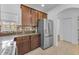 Kitchen with stainless steel refrigerator, dark wood cabinets, mosaic tile backsplash and neutral tile floor at 5030 Herring Ct, New Port Richey, FL 34652