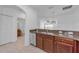 Open kitchen layout with stainless steel dishwasher and sink, dark wood cabinets, and view to the living area at 5030 Herring Ct, New Port Richey, FL 34652