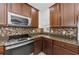 Kitchen featuring stainless steel appliances, dark wood cabinets, mosaic tile backsplash, and granite countertops at 5030 Herring Ct, New Port Richey, FL 34652