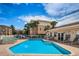 A pool and patio area sit between a condo building and a small amenity center with lounge chairs and tables at 5030 Herring Ct, New Port Richey, FL 34652