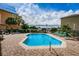 Community pool with stairs, lounge chairs, shady trees, and community buildings under a cloudy blue sky at 5030 Herring Ct, New Port Richey, FL 34652