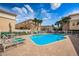 Community pool area with lounge chairs, tables, and view of the condo buildings on a beautiful sunny day at 5030 Herring Ct, New Port Richey, FL 34652