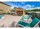 Community pool with lounge chairs and tables under a covered patio with beautiful landscaping in the background at 5030 Herring Ct, New Port Richey, FL 34652