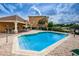 Outdoor pool with chairs, covered area, tables and chairs, and beautiful weather with buildings in the background at 5030 Herring Ct, New Port Richey, FL 34652