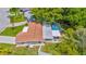 Aerial view of home with a screened pool, mature trees, fenced yard, and neutral toned roof at 5102 Peacock, Holiday, FL 34690