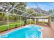 Sparkling pool inside a screened enclosure with lush green backyard at 5102 Peacock, Holiday, FL 34690