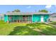 Back of house featuring screen room, turquoise exterior walls, and a manicured lawn at 5107 Pine St, Seffner, FL 33584