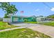 A well-maintained turquoise home with a carport, American flag, and neatly landscaped lawn at 5107 Pine St, Seffner, FL 33584