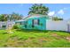 Charming turquoise home featuring mature landscaping, a white picket fence, and an American flag at 5107 Pine St, Seffner, FL 33584
